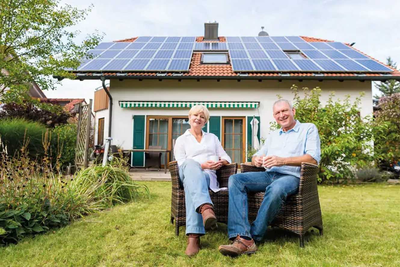 Zufriedene Kunden von Solarleasing-Anbieter Enpal im Garten vor dem eigenen Haus mit PV-Anlage