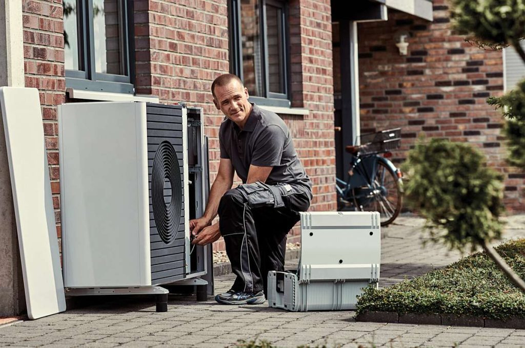 Ein Installateur installiert eine Wärmepumpe und trägt so zum Wärmepumpen-Boom in Deutschland bei