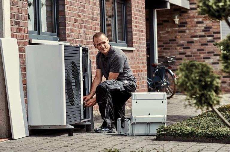 Ein Installateur installiert eine Wärmepumpe und trägt so zum Wärmepumpen-Boom in Deutschland bei