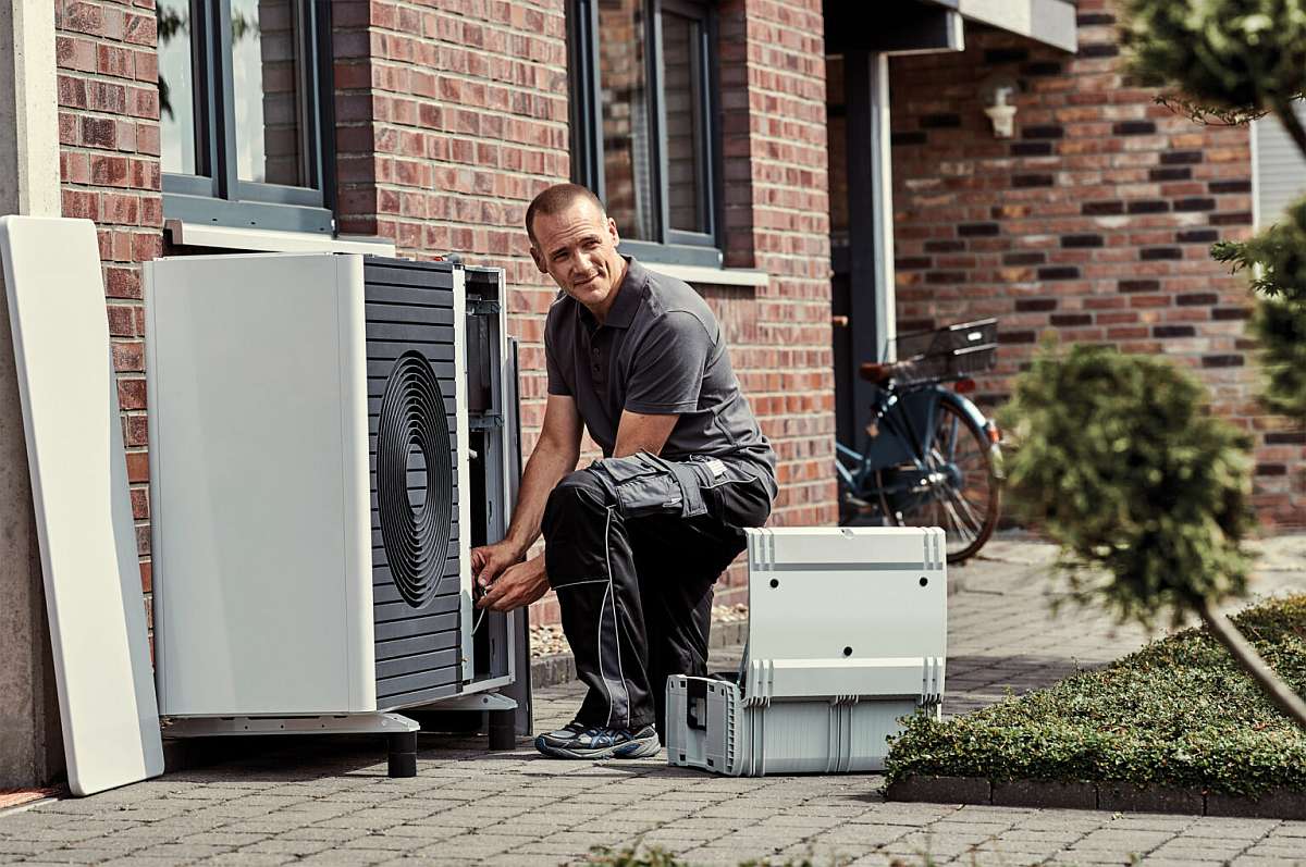 Ein Installateur installiert eine Wärmepumpe und trägt so zum Wärmepumpen-Boom in Deutschland bei