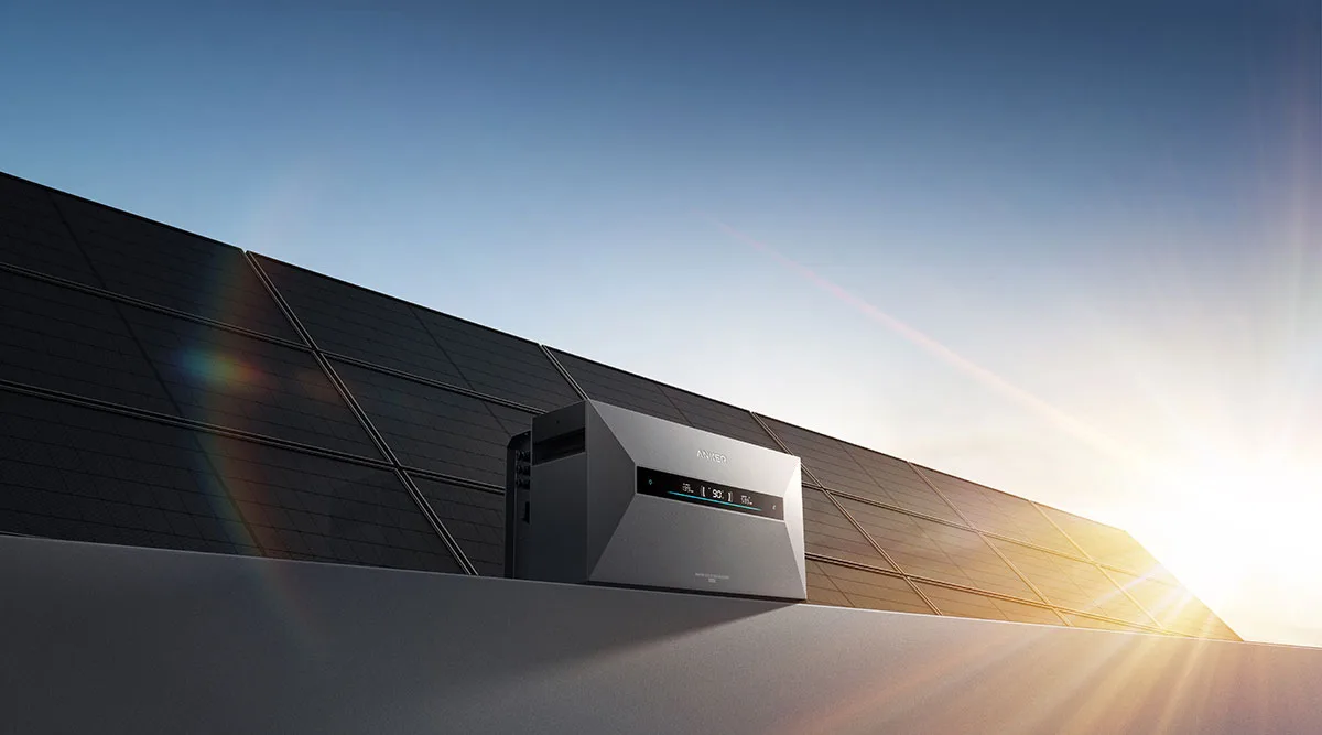 Anker SOLIX Solarbank Max vor einer Reihe Solarmodule auf einem Flachdach im Gegenlicht