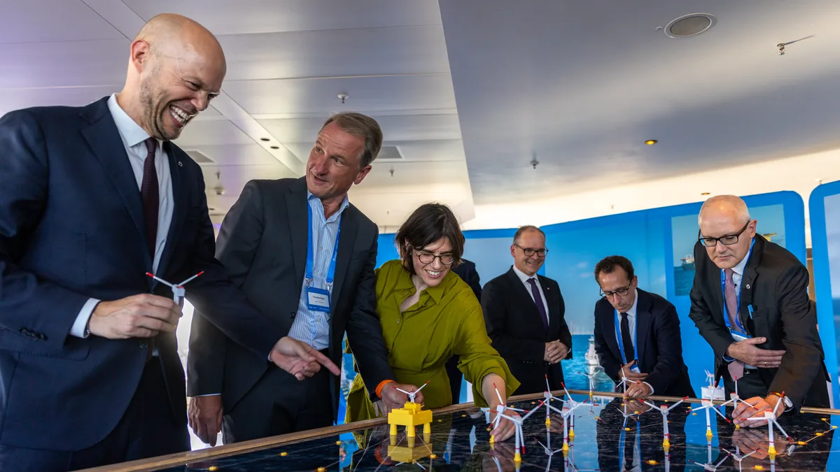 Einweihung von Borkum Riffgrund 3 in Hamburg: Gäste an einem Modell eines Offshore-Windparks mit Windkraftanlagen und Konverterplattform