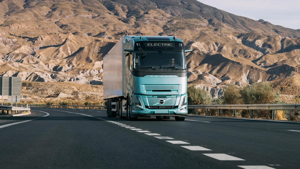Elektrischer Sattelzug Volvo FH Aero Electric mit Kühlauflieger auf einer Autobahn in hügeliger Landschaft