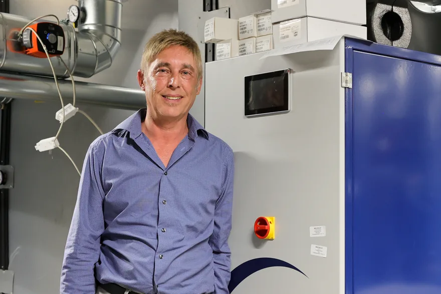 Planer Robert Mueller steht neben einer eXergiemaschine im Technikraum