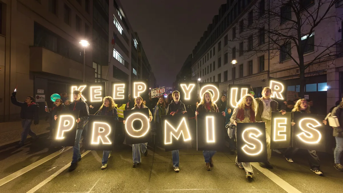 Junge Menschen tragen bei einer nächtlichen Demonstration in Berlin leuchtende Buchstaben mit der Aufschrift Keep your promises