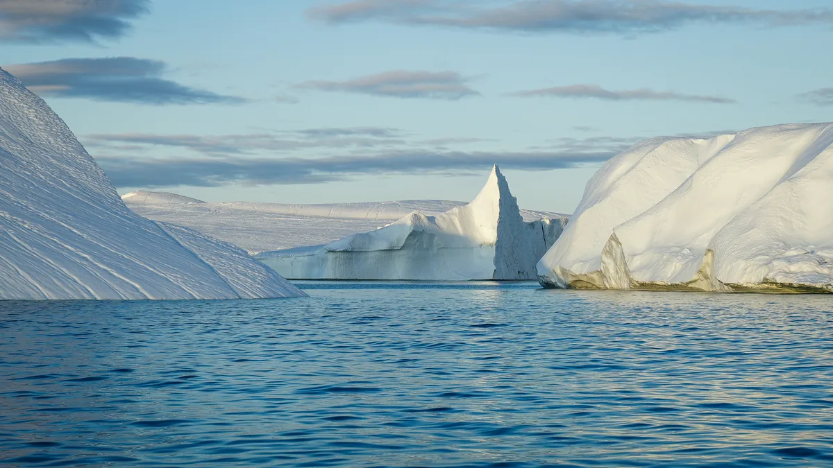 Eisberge im Meer vor Grönland bei tiefstehender Sonne, Symbolbild für die Erderhitzung im Hitzesommer 2026