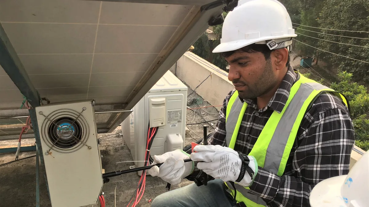 Installateur montiert eine Solaranlage auf einem Dach in Pakistan