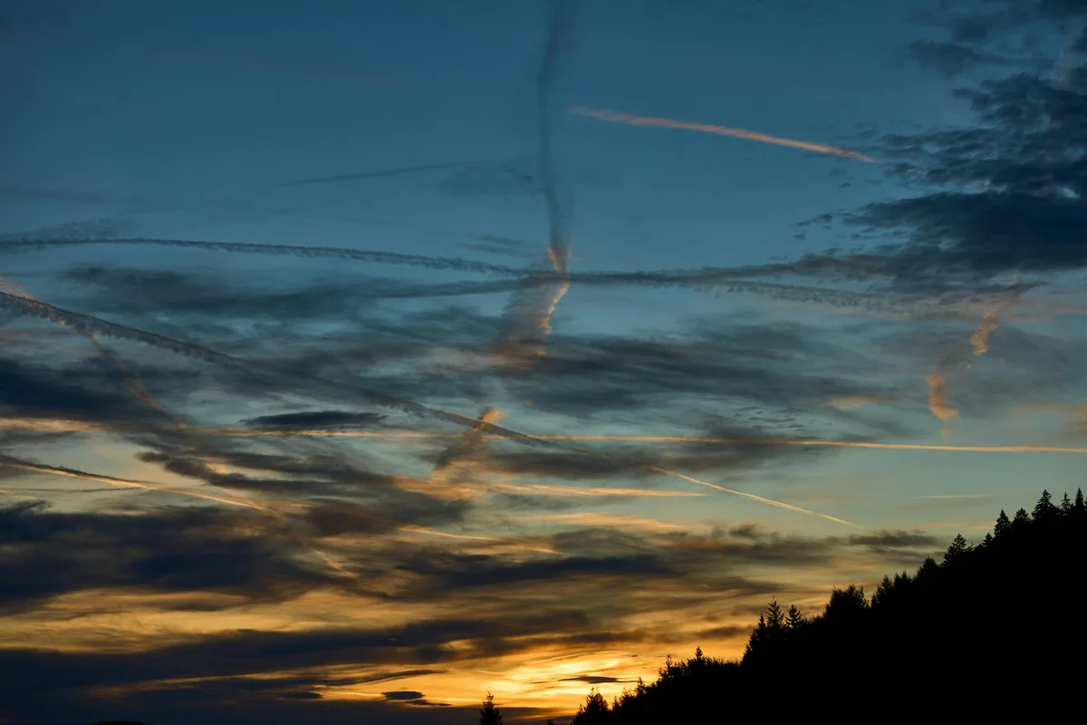 Kondensstreifen am Abendhimmel, die zu Schleierwolken zerfasern