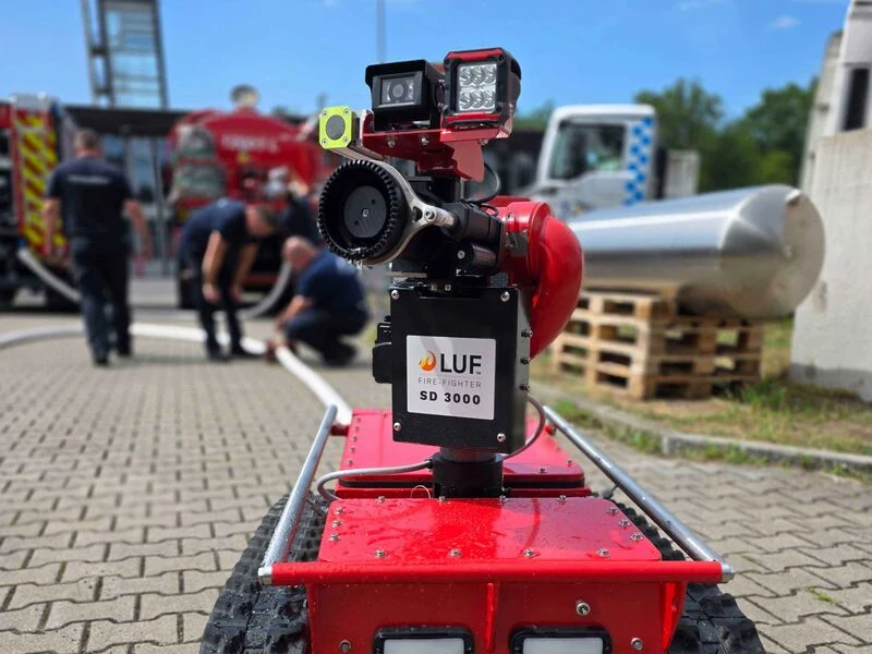 Ferngesteuerter Löschroboter LUF Nano mit Kameramodul und Löschmonitor SD 3000, im Hintergrund Einsatzkräfte der Feuerwehr.