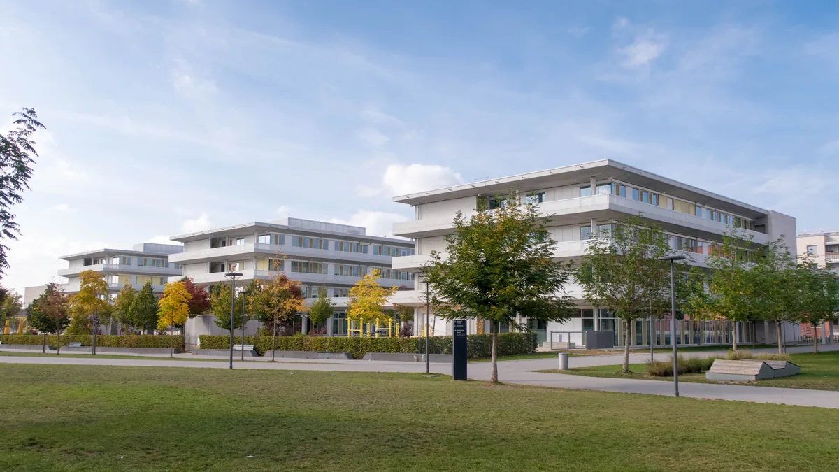 Mehrgeschossige Gebaeude im Quartier Freiham in Muenchen, davor Rasen und Herbstbaeume