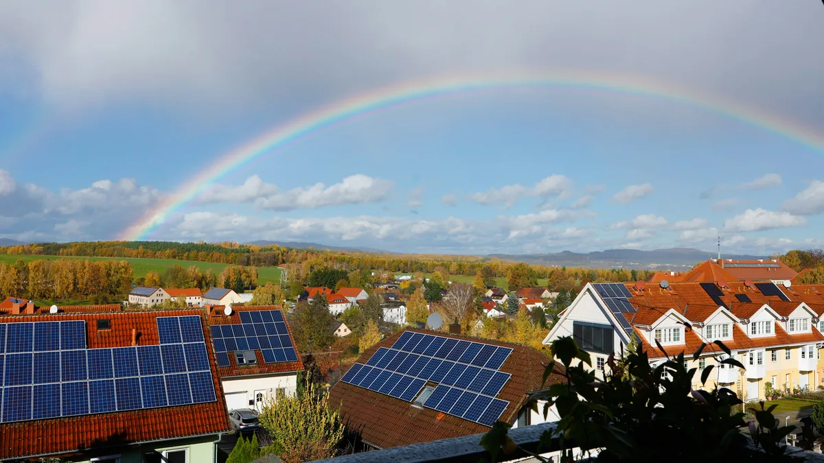 Solardächer in einer Wohnsiedlung unter einem Regenbogen